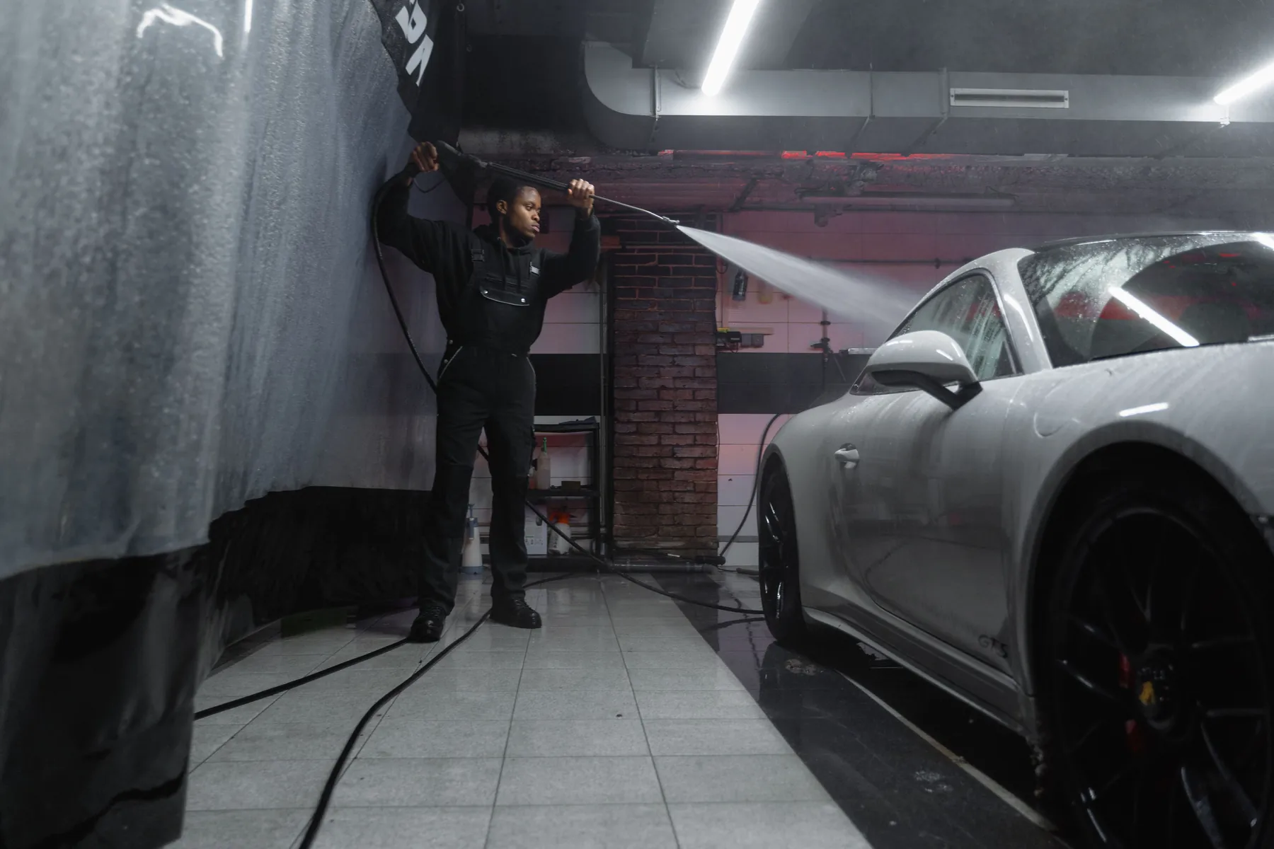 Technician pressure rinsing a white car